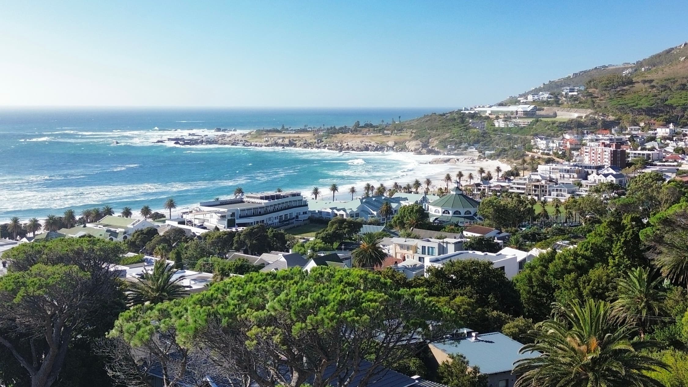 Aerial view over Camps Bay — the beachfront, palms and Atlantic seaboard from above